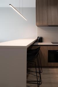 a kitchen with a white counter and a black stool at Apartament Legionów- A15 w centrum Kalisza in Kalisz