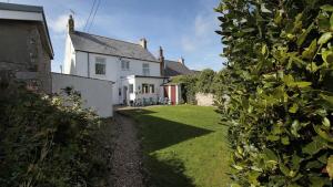 una casa blanca con un patio de césped y una casa en Carreg Lwyd Farmhouse, en Port Eynon