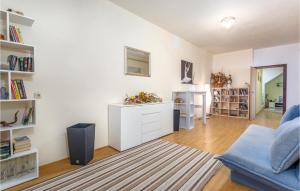 a living room with a blue couch and a book shelf at Stunning Apartment In Stara Baska in Stara Baška