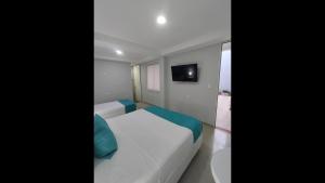 a bedroom with a white bed and a television at Bm-7 room near the sea with air conditioning and WIFI in Cartagena de Indias
