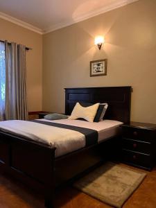 - une chambre avec un grand lit et une tête de lit en bois dans l'établissement Ibanya Havens, 