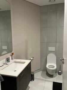 a bathroom with a sink and a toilet and a mirror at Triology Menlyn Maine Residences in Pretoria