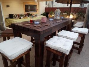 a wooden table with white cushioned chairs around it at VILLA AVATOS - Near to the port of Rafina and the airport of Athens in Áyios Spirídhon