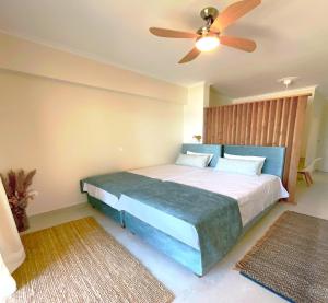 a bedroom with a blue bed with a ceiling fan at Beachfront 2-bed luxury Apartment - Agios Gordios Corfu Greece in Agios Gordios +18 photos