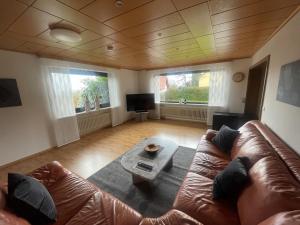 a living room with a leather couch and a table at Ferienwohnung Janz Jürgen und Bianka in Oberelsbach