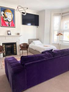 sala de estar con sofá púrpura y cama en La Di Da Hotel beach town, en Bournemouth