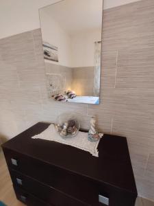 eine schwarze Kommode mit einem Spiegel darüber in der Unterkunft Appartamento vicino Grado/Aquileia in San Lorenzo