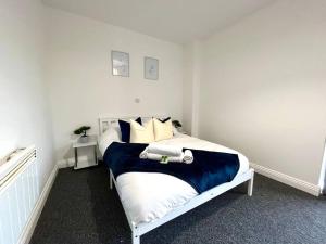 a white bedroom with a bed with blue and white pillows at Lorne Park Road, Bournemouth in Bournemouth