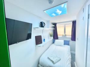 mały pokój z łóżkiem i telewizorem z płaskim ekranem w obiekcie Coastline Retreats - Cloud9 Newly Renovated, Beautiful Ensuite Rooms Near Seafront in Town Centre, Netflix, SuperFast WiFi, Communal Kitchen w Bournemouth