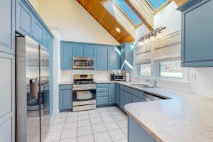 Edgartown Retreat في إدغارتاون: مطبخ مع دواليب زرقاء ونافذة كبيرة
