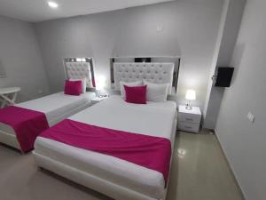 two beds in a hotel room with red and white sheets at Bm-1 room near the sea with air conditioning and WIFI in Cartagena de Indias