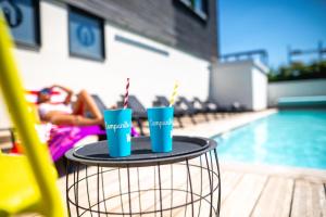 deux tasses bleues sur une table à côté d'une piscine dans l'établissement Campanile Carcassonne Est - La Cité, à Carcassonne