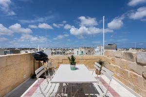 d'une table et de chaises blanches sur un balcon. dans l'établissement Authentic Maltese 2-bedroom House with Terrace, à Żejtun