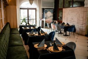 une rangée de tables dans un restaurant avec des tables et des chaises noires dans l'établissement Villa Tradycja, à Białystok