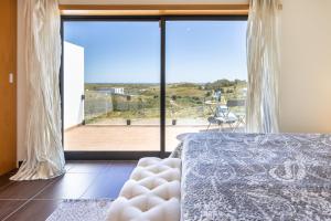 a bedroom with a bed and a large window at Margarida Sun House Ocean View in Raposeira