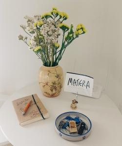 un tavolo con un vaso con fiori e un piatto di A Casa Mia a Matera