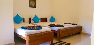 2 camas individuales en una habitación con almohadas azules. en Yapagama Village, en Dambulla