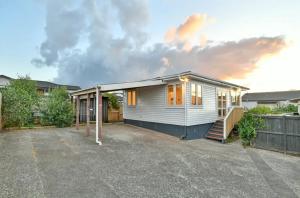 a small white house with a driveway at Cute and Cozy near Airport in Auckland