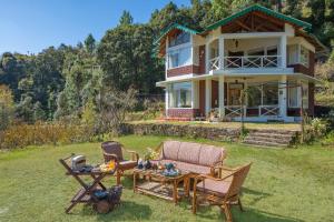 une maison avec des chaises et une table dans la cour dans l'établissement Hollyhock Cottage by VEO - Part of StayVista, à Rāmgarh