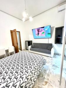 ein Wohnzimmer mit einem Sofa und einem TV in der Unterkunft Mi casa tu casa - Guest House in Catania