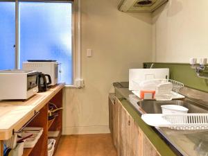 a kitchen with a sink and a microwave at コトリ コワーキング&ホステル高松 in Takamatsu
