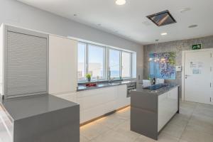a kitchen with white and gray counters and windows at Sai Gayatri in Nerja