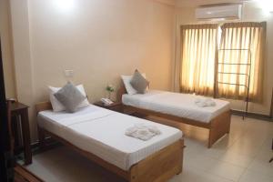 a hotel room with two beds and a window at Hotel Oviya in Vavuniya