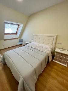 - une chambre avec un grand lit blanc et une fenêtre dans l'établissement Centro de Miño - Pumariega, à Miño