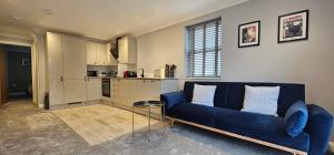ein Wohnzimmer mit einem blauen Sofa und einer Küche in der Unterkunft The Philog by Switchback Stays in Cardiff
