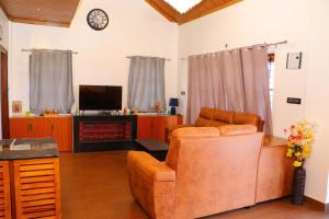 ein Wohnzimmer mit einem Sofa und einem TV in der Unterkunft The Frame Resorts Ooty in Udagamandalam