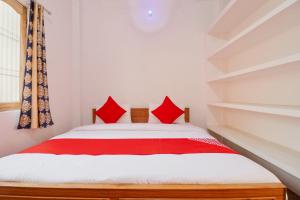 a bedroom with a bed with red pillows at Super OYO New Suhani House in Rāmnagar