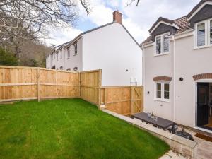 a backyard with a wooden fence and green grass at Conybeare Cottage in Lyme Regis
