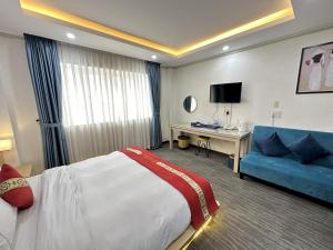 a hotel room with a bed and a blue couch at Capital O 1177 Saigon Sweet Hotel in Ho Chi Minh City