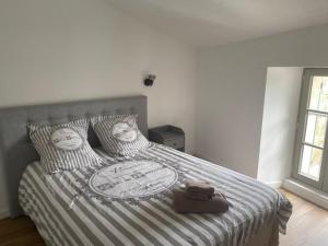 a bedroom with a bed with a striped comforter and pillows at HOME ET HOLIDAY Le Petit Verdot in Viviers