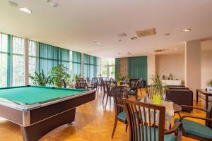 a pool table in a room with tables and chairs at Hotel Fit Hévíz in Hévíz