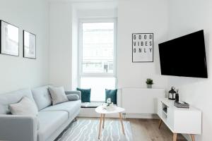 a white living room with a couch and a tv at Deluxe Flat, PS4, Parken, Netflix, Zentral in Offenbach