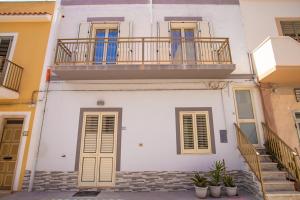 un edificio bianco con balcone e scale di La Scala del Moro Rooms - Dolce Risveglio a Lampedusa