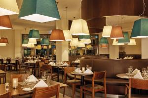 a restaurant with tables and chairs and chandeliers at HYPERION Hotel Hamburg City, Trademark Collection by Wyndham in Hamburg