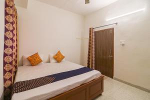 a bedroom with a bed with orange pillows on it at SPOT ON Hotel Om Kanha in Bilāspur