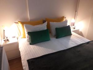 a large bed with two green pillows on it at Apartmani Kosic in Banja Luka