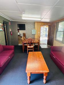a living room with a wooden table and red couches at Carinya Village Jindabyne in Jindabyne