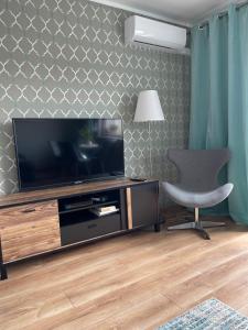 a living room with a television and a chair at Apartament Centrum in Lidzbark Warmiński