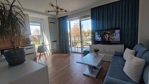 un salon avec un canapé bleu et une télévision dans l'établissement TURKUS, à Świnoujście