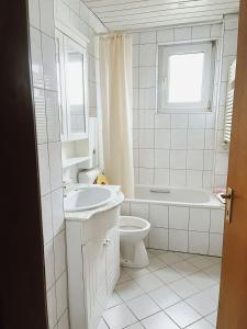 a white bathroom with a sink and a toilet at Messezimmer Laatzen 30880 in Hannover