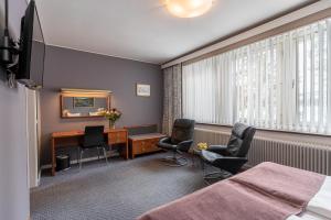 een hotelkamer met een bureau en 2 stoelen bij Hotell Villa Sparta in Älvsbyn