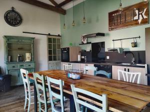 a kitchen with a wooden table and white chairs at Les Trois Jolies in Maylis