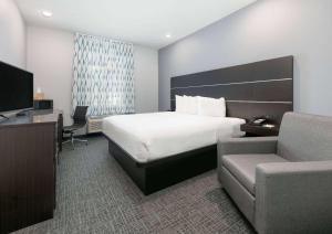 a hotel room with a bed and a desk and a chair at Days Inn by Wyndham Zachary LA in Zachary