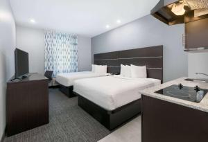 a hotel room with two beds and a sink at Days Inn by Wyndham Zachary LA in Zachary +37 photos