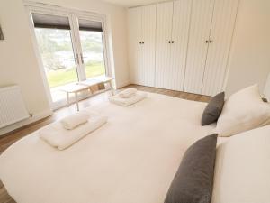 Cette chambre comprend un grand lit blanc et une fenêtre. dans l'établissement 2 The Dunes, à Falmouth