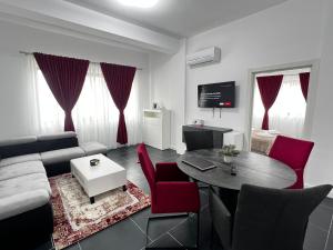 a living room with a couch and a table and red chairs at Luxury Cozy Apartments - City Center Suceava in Suceava